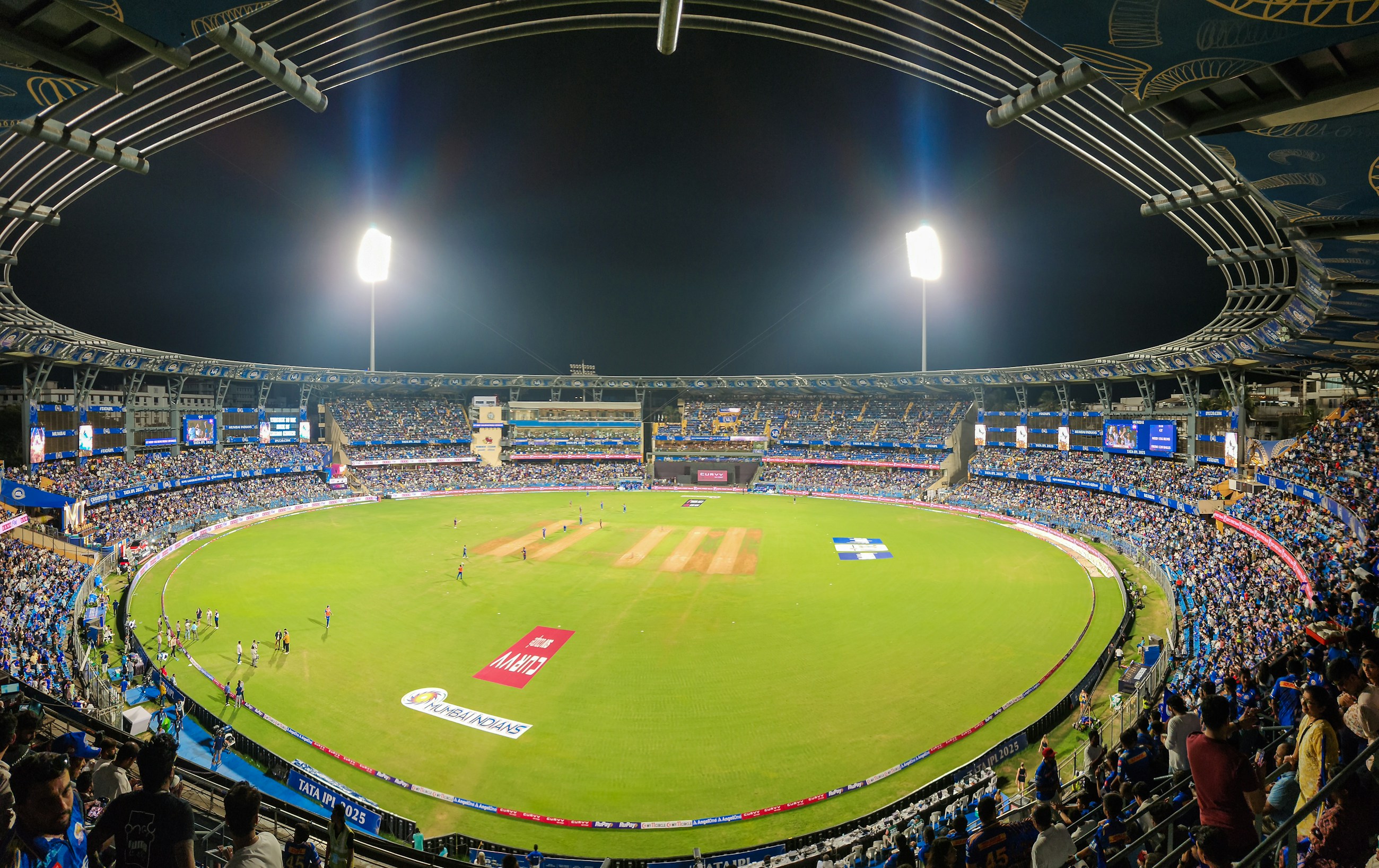 Packed floodlit cricket stadium at night